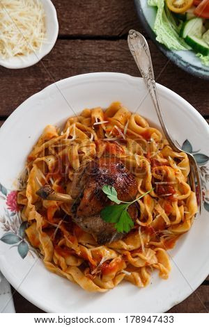 Italian homemade pasta, pappardelle with tomato sauce and braised rabbit, top view close-up.