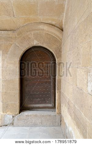Wooden aged vaulted ornate door and stone wall at caravansary (Wikala) of Bazaraa Medieval Cairo Egypt