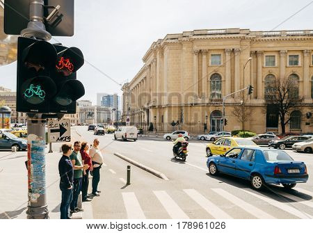BUCHAREST ROMANIA - APR 1 2016: Pedestrians waiting to cross the Calea Victoriei Boulevard avenue with the The National Museum of Art of Romania in the background
