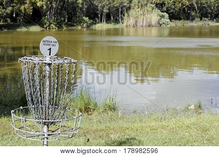 Oakland Park FL USA - November 8 2016: Easterlin Park Frisbee Golf sign on a goal post basket target by a lake. Disc golf basket hole and sign on a sunny day.