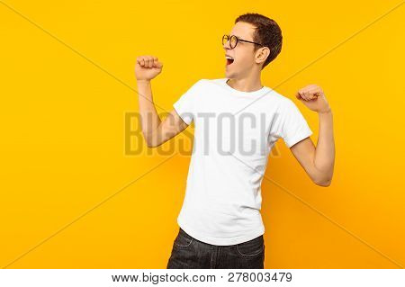 Man In Glasses, Dressed In A White T-shirt, The Man Who Won Shows A Gesture Of Victory And Success,