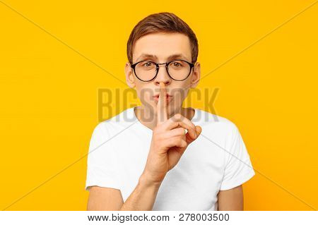 The Guy In The White T-shirt In Round Transparent Glasses Says: Shhhh, Shows Silent Gesture, On A Ye