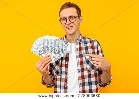 Happy Man In Glasses And A Plaid Shirt, With Dollar Bills, On Yellow Background