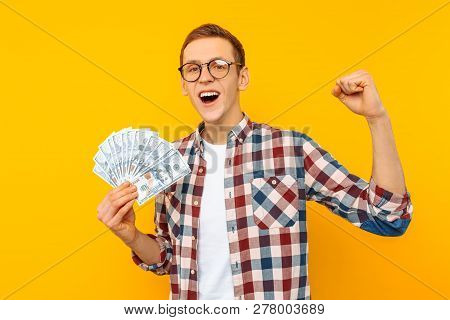 Screaming Man In A Plaid Shirt Holds Money In His Hands And Looks Into The Camera On A Yellow Backgr