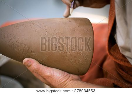 Ceramic Workshop, The Master Puts Otnament On Unfired Earthenware Jug. Close-up Of Master Hands. Mad