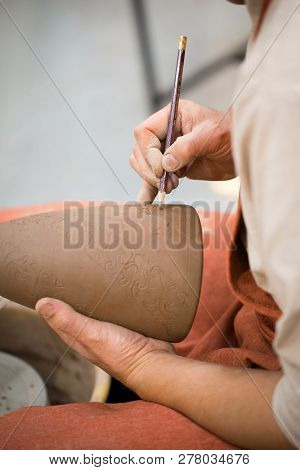 Ceramic Workshop, The Master Puts Otnament On Unfired Earthenware Jug. Close-up Of Master Hands. Mad