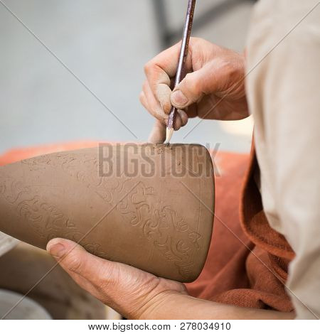 Ceramic Workshop, The Master Puts Otnament On Unfired Earthenware Jug. Close-up Of Master Hands. Mad