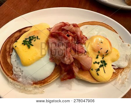 Salted Pancakes With Hollandaise Suace, Eggs And Crispy Bacon For Breakfast. Salty Fast Food.