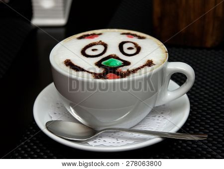 A Cup Of Cappuccino On A Saucer. There Is A Pattern In The Form Of A Smiling Face.