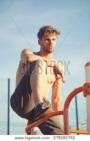 Macho Relax After Workout Outdoor. Man Athlete Climb On Metal Jungle Gym On Blue Sky. Sportsman With