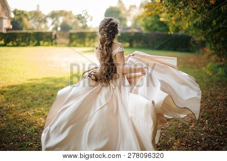 Back View Of Beautiful Bride Spinning In A Wedding Dress Dancing On The Green Field