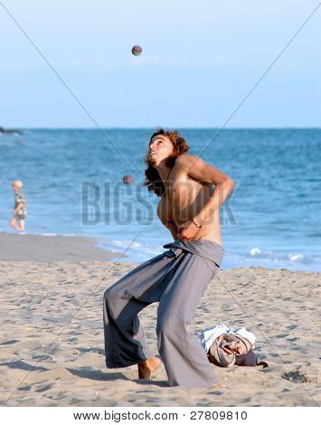 Young street performer Juggling su una spiaggia della California