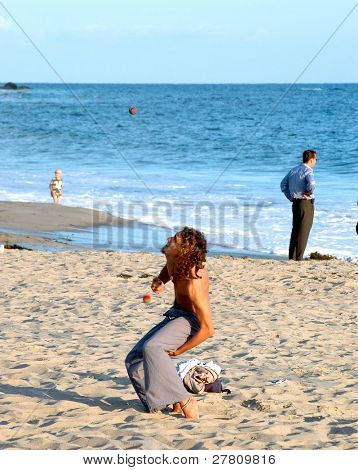 Young street performer Juggling su una spiaggia della California