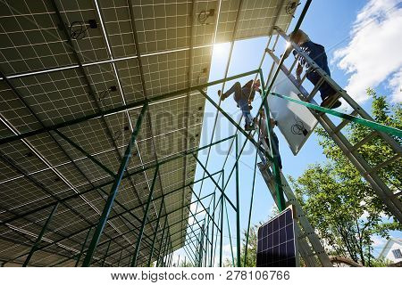 Mounters Team Installing Solar Batteries On Houses Roof. Mounting Solar Panels On Green Metallic Car