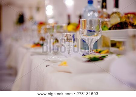 Festive Tableware With Glasses On A Table. Empty Glasses Stand Near Plates And Forks On Banquet Tabl