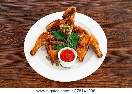Grilled Fried Roast Chicken Tabaka On A Plate On A Wooden Background, Top View