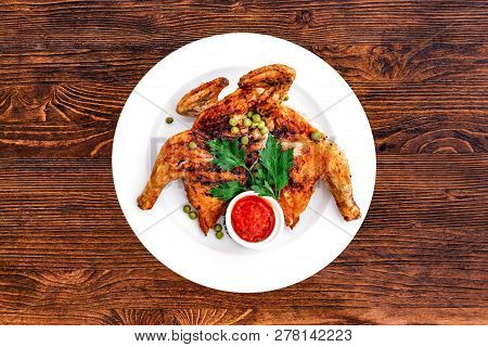 Grilled Fried Roast Chicken Tabaka On A Plate On A Wooden Background, Top View