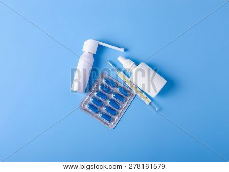 Blue Pills Capsules Nose Throat Spray Cough Syrup Thermometer Medicine Health On Blue Background Top