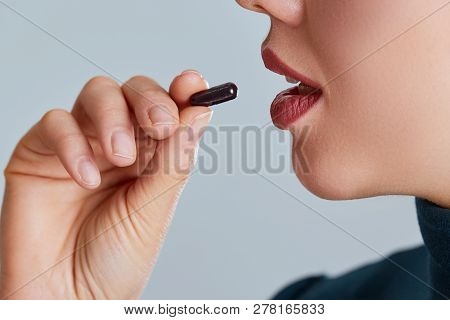 Vitamin And Supplement. Closeup Of Beautiful Young Woman Taking Yellow Fish Oil Pill. Female Hand Pu