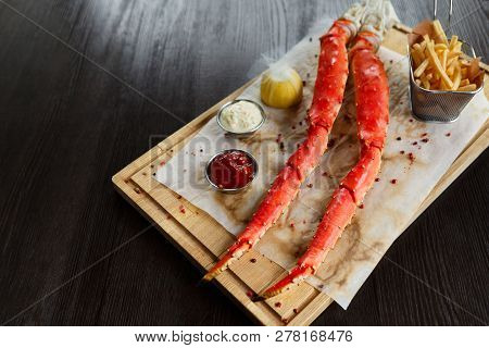 Gourmet Food. Cooked King Crab Legs With Sauces And French Fries On Wooden Board, Copy Space