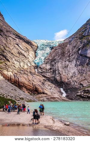 Norway, Olden - August 1, 2018: People At Near Lake And Briksdal Or Briksdalsbreen Glacier With Melt