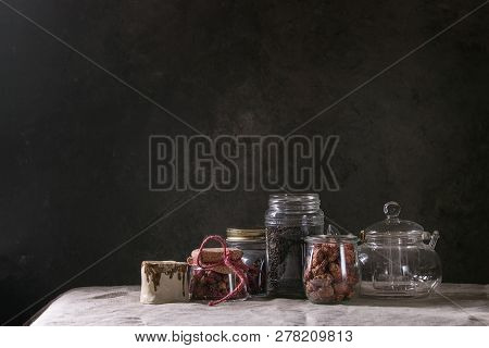 Tea Collection. Black Dry Tea In Jar, Rose Buds, Empty Glass Teapot, Cream Jug, Sweet Sugared Almond