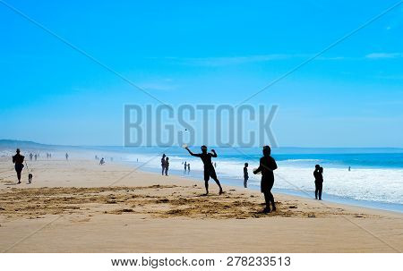 Silhouete Of People Playing Beach Racket At Costa Da Caparica Beach. Lisbon, Portugal