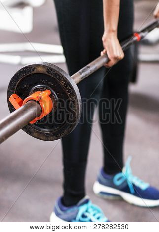 A Young High School Female Track Runner Is Learning How To Do Cleans While Lifting Weights In The We