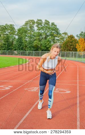 Athletic Woman On Running Track Has Side Cramps During Workout