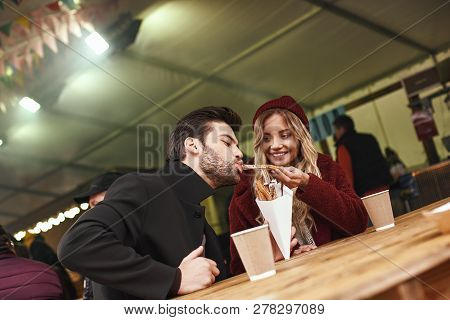Close-up Of Young Couple Are Eating Churros At The Street Food Market.