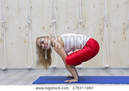 Beautiful Smiling Happy Young Woman Working Out Indoors, Doing Yoga Exercise On Blue Mat