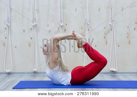 Beautiful Smiling Happy Young Woman Working Out Indoors, Doing Yoga Exercise On Blue Mat