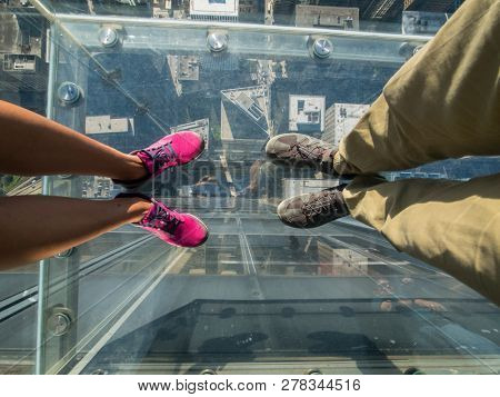 Tourists posing on a glass floor in a skyscraper