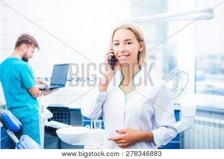 Dental doctor talking on smartphone in stomathology office