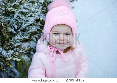 Portrait Of Little Toddler Girl Walking Outdoors In Winter. Cute Toddler Eating Sweet Lollypop Candy