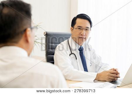 Portrait of Young adult Doctor with Patient in examination room medical office.