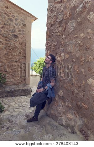 Caucasian Young Man Relaxing On A Wall In Banyalbufar Majorca. Selective Focus