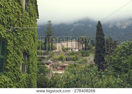 10 May 2018 Deia, Majorca. Beautiful Country Houses And Lush Greenery And Palm Trees In Cloudy Day. 