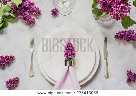Spring Table Place Setting With Lilac Flowers, Silverware On Light Table. Top View.
