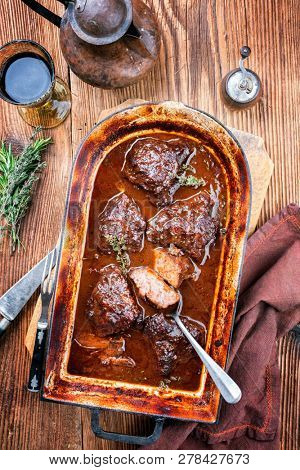 Traditional German braised veal cheeks in brown sauce with mushroom and onions as top view in a stewpot 