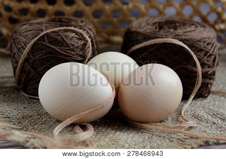View Straight Three Eggs, Knitting Yarn On The Background Of A Beige Basket. Lie On A Dark Backgroun