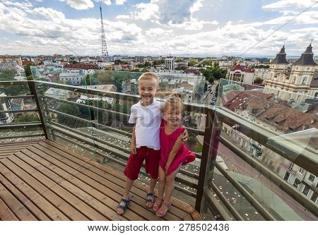Two Smiling Happy Little Children Boy And Girl Standing On Top Of View Deck Of High Building With Ci