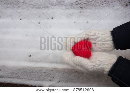 Hands In White Mitterns With Red Heart On The Snow Background