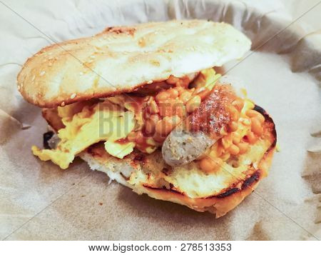 Grilled toasts served with beans, scrumbled eggs and sausage for an English breakfast