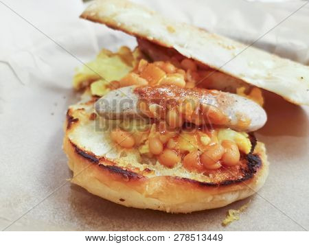 Grilled toasts served with beans, scrumbled eggs and sausage for an English breakfast