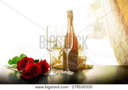 Bottle Of Champagne And Two Glasses With Rose Flowerin The Room.