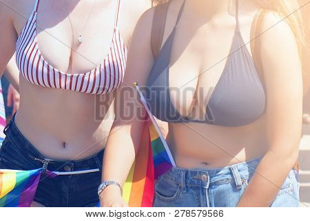Gay And Lesbians Walking In The Gay Pride Parade. An Image Of Two Girls In A Swimsuit To The Waist. 