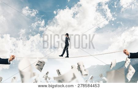Businessman Walking Blindfolded On Rope Among Flying Documents And Above High Mountains As Symbol Of
