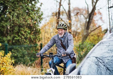 Active Senior Man With Electrobike Cycling Outdoors In Park.