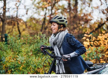 Active Senior Woman With Electrobike Cycling Outdoors In Park.